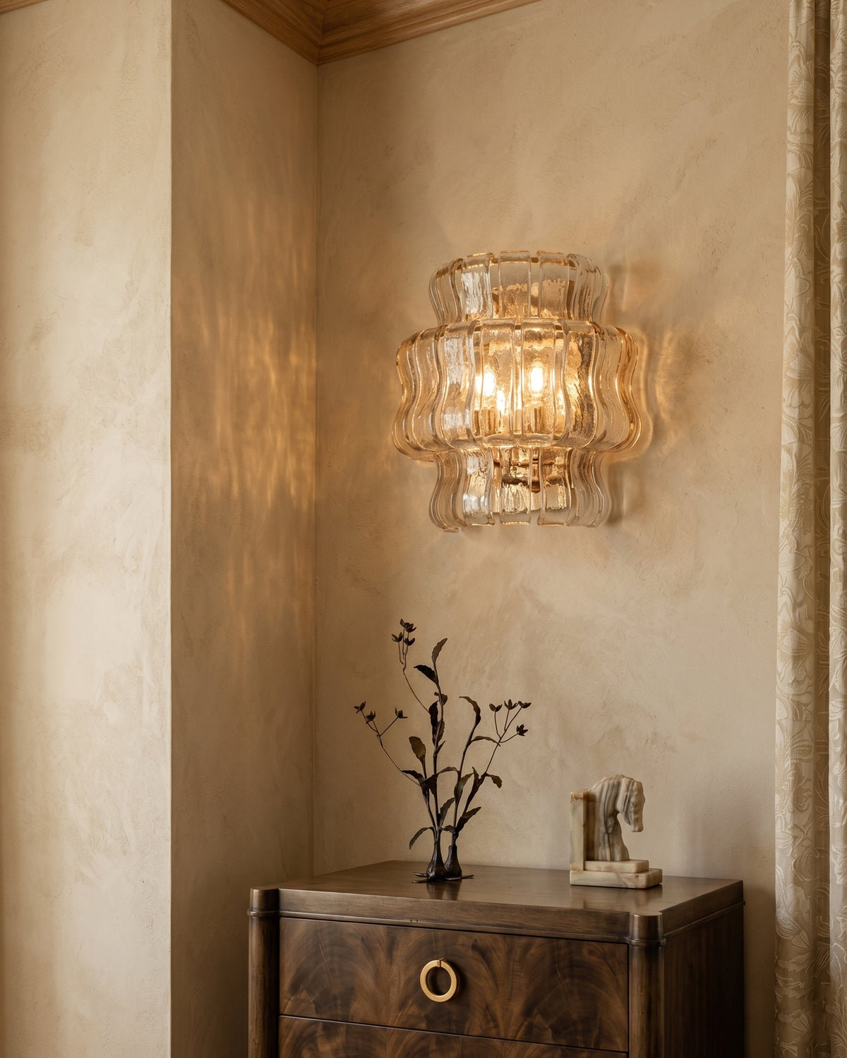 The Albano Wall Lamp in amber glass casting a warm glow.
