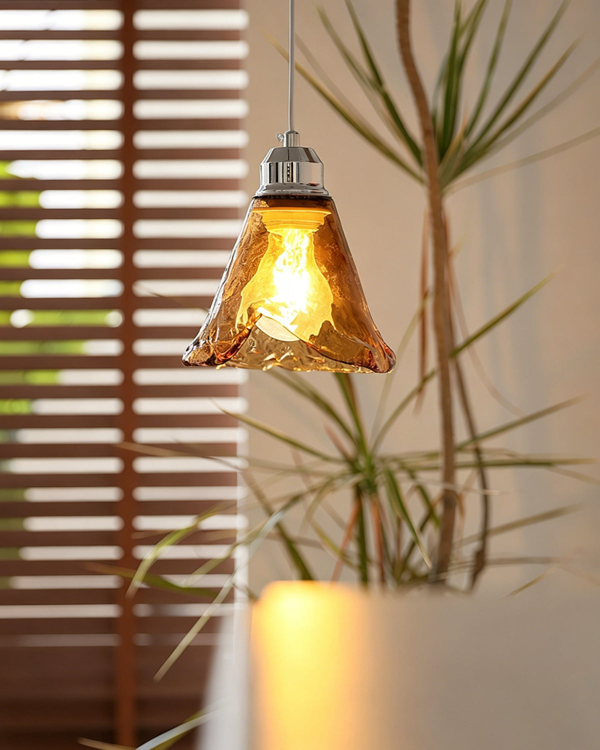 Lifestyle image of the Tiro Glass Pendant Light in a contemporary living room setting.